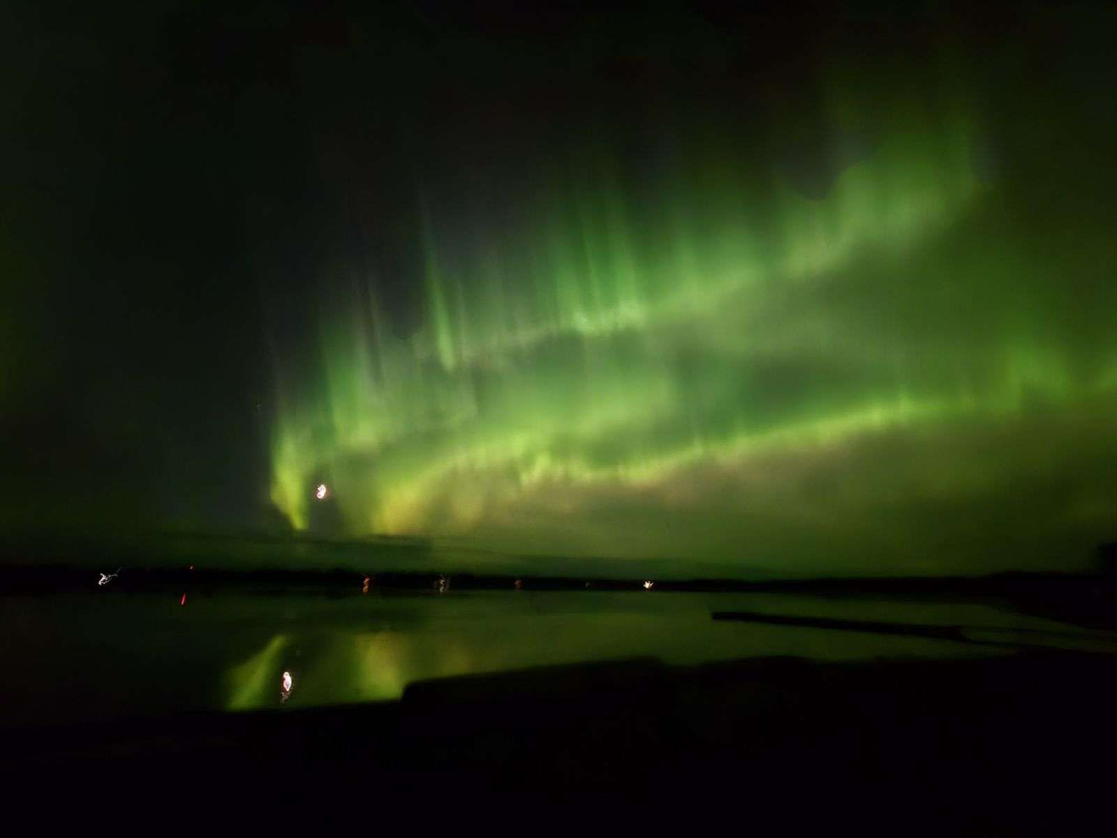 Bright green curtains of aurora hanging over the water.