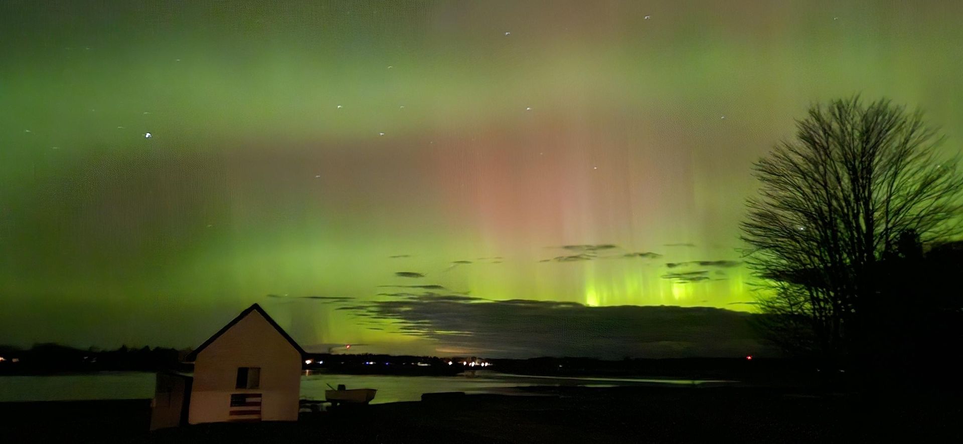 Green northern lights stretching across the night sky over Little Bay De Noc.