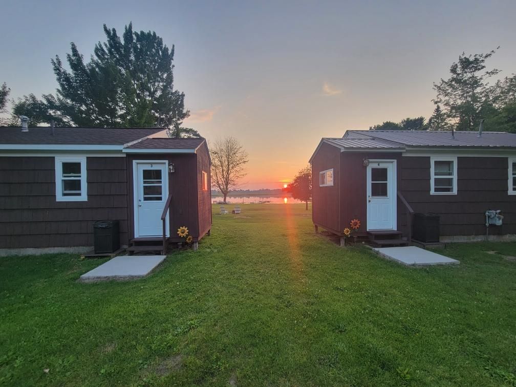 Two of our cabins facing the water while the sun sets between them.