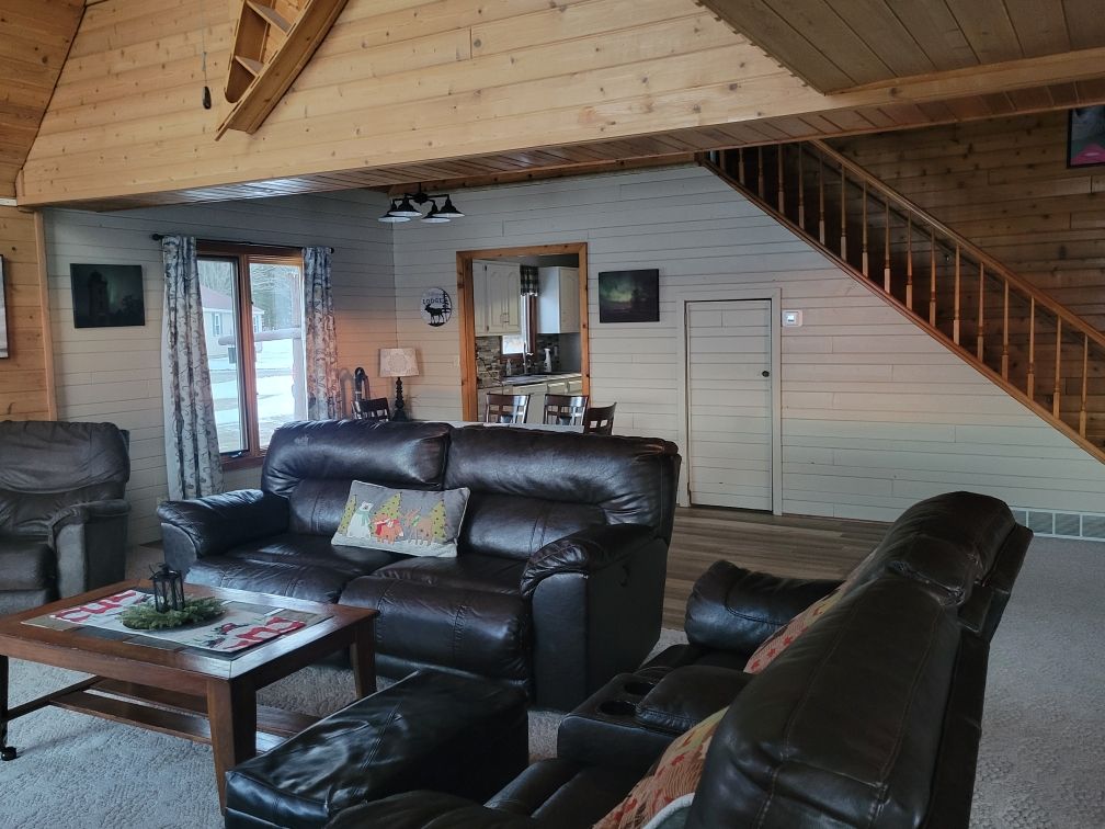 Leather couches inside the lodge, with the stairs climbing to the loft.